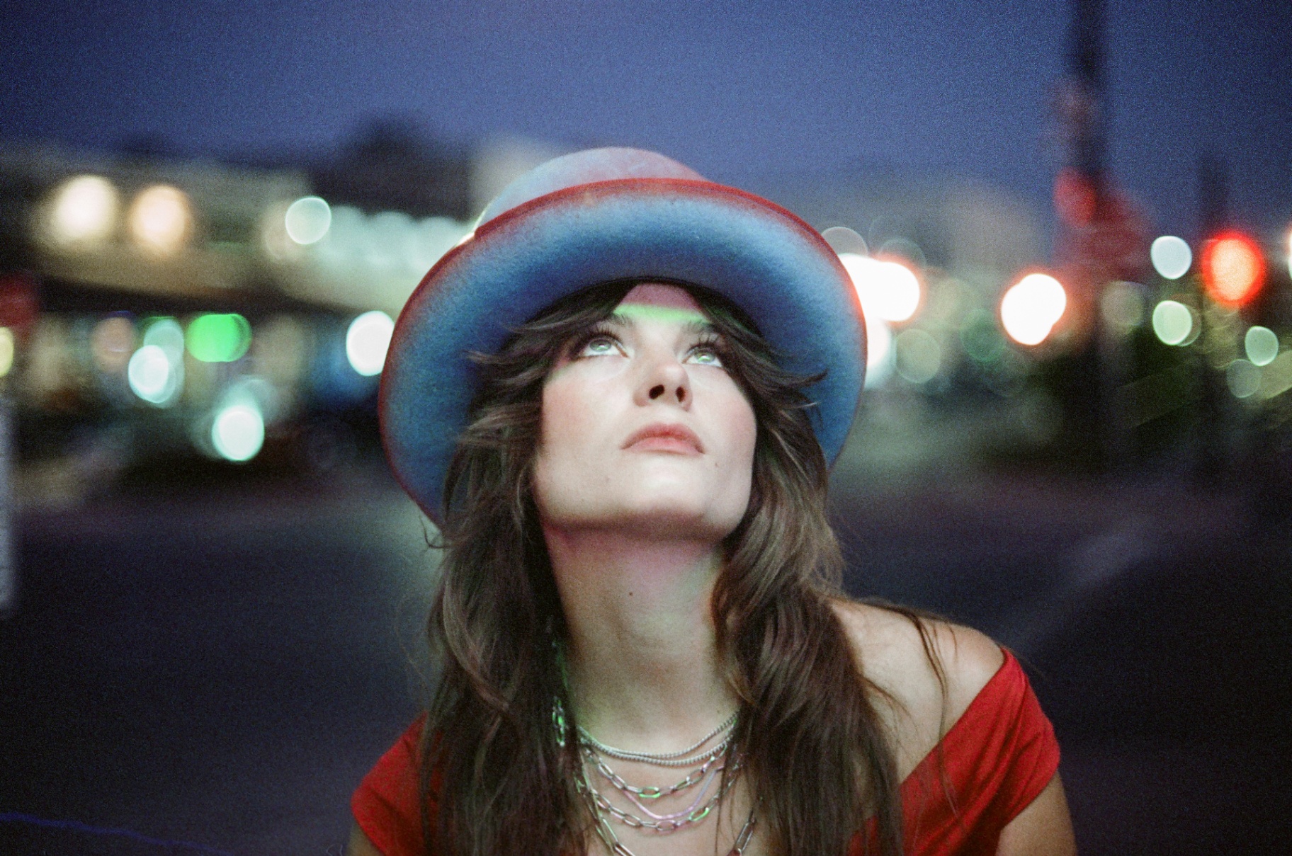 Original 35mm portrait of a woman in a wide-brim hat beneath city lights at night