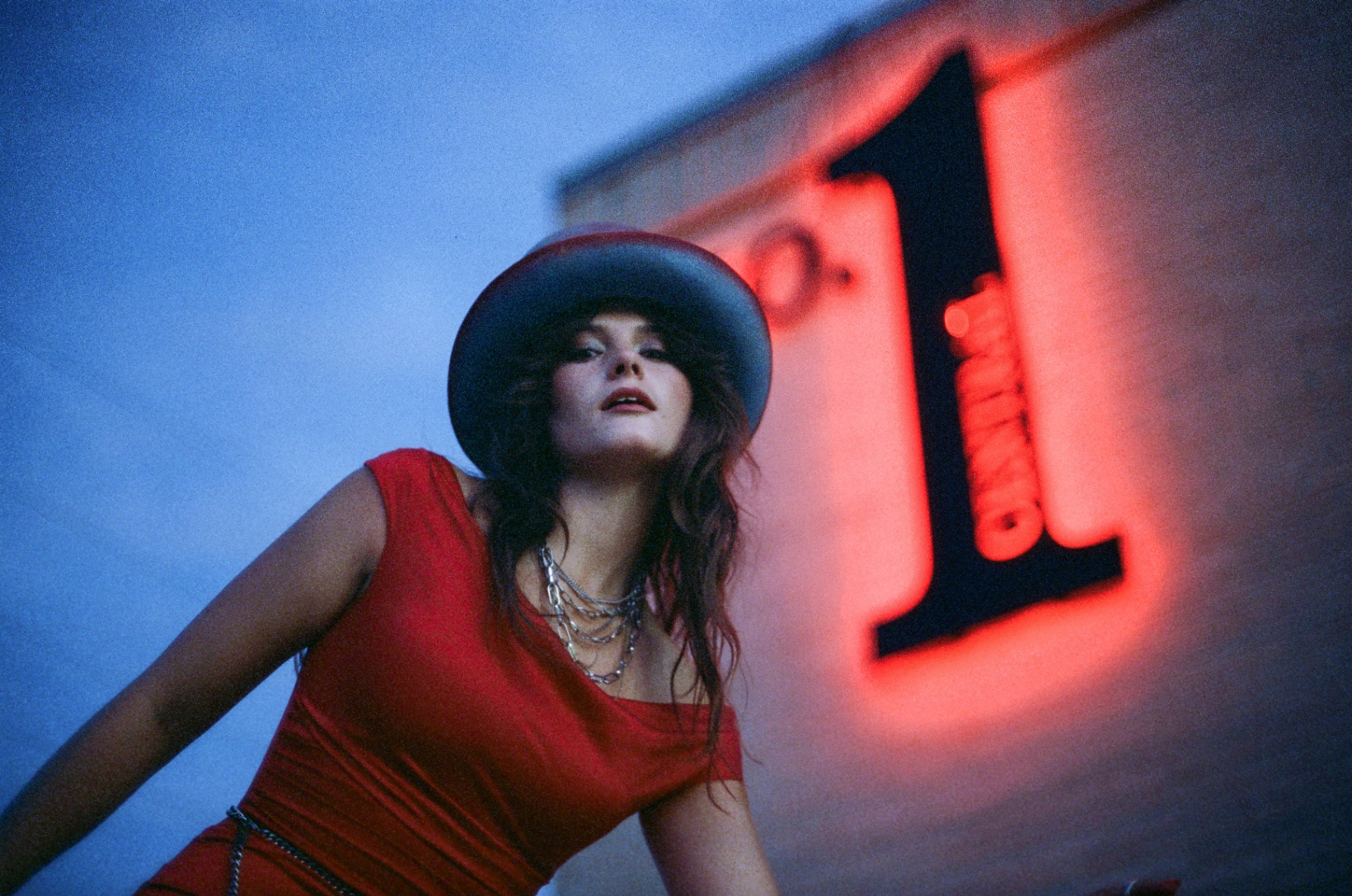 Original 35mm full-length portrait of a woman in a red dress standing before a lit garage door at night