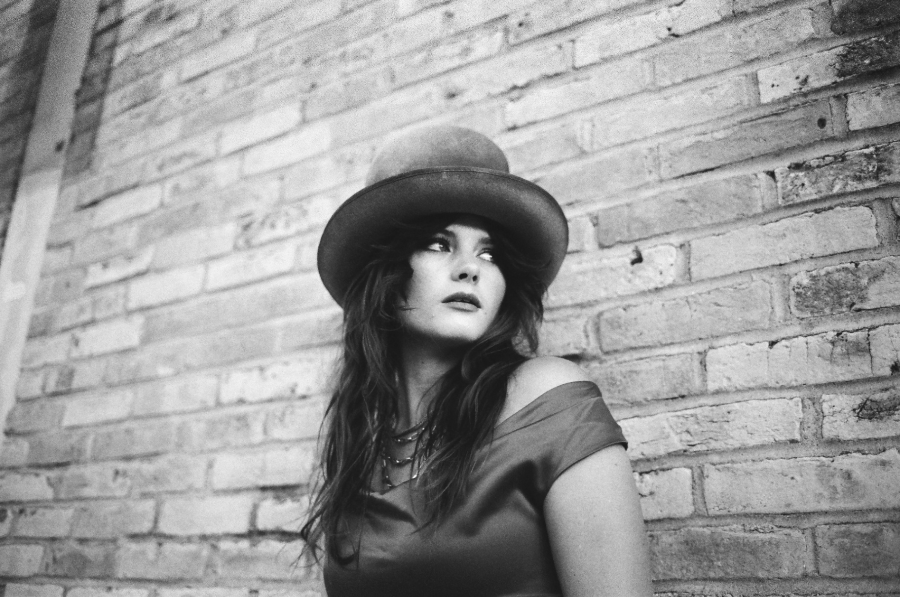 Original black and white 35mm portrait of a woman in a bowler hat against a brick wall