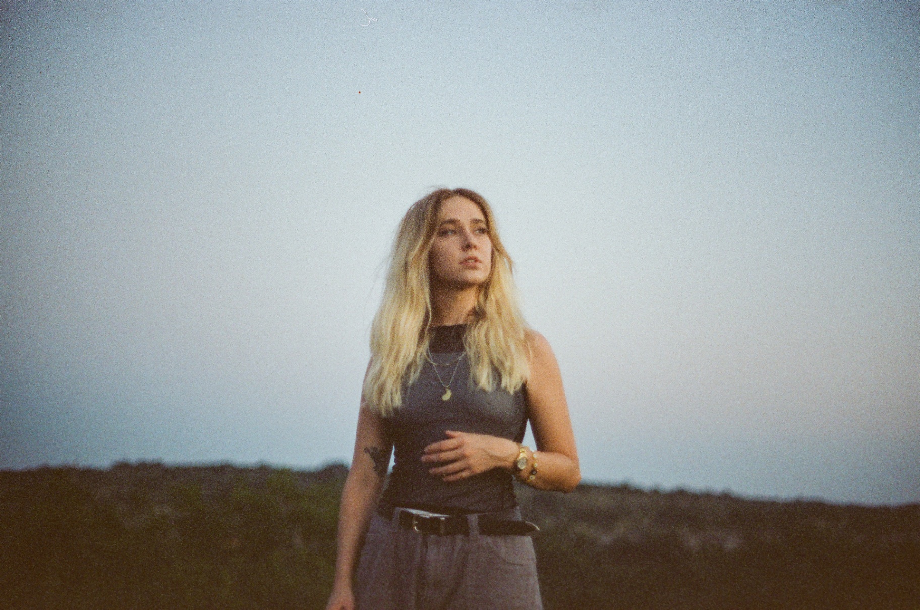 Original 35mm portrait of a blonde woman standing in tall grass at dusk looking into the distance