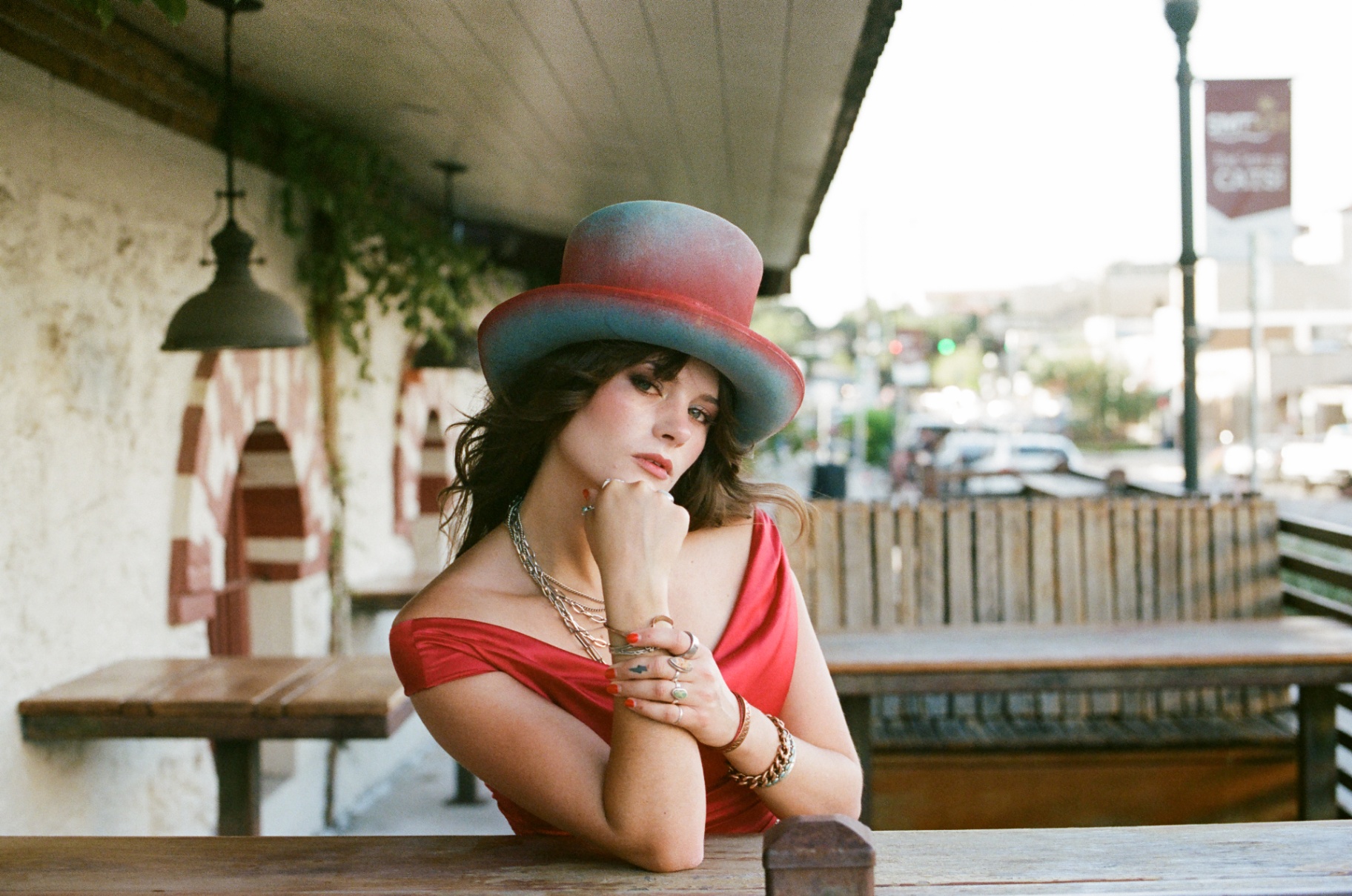 Original 35mm portrait of a woman in a red dress and painted hat resting at a patio table