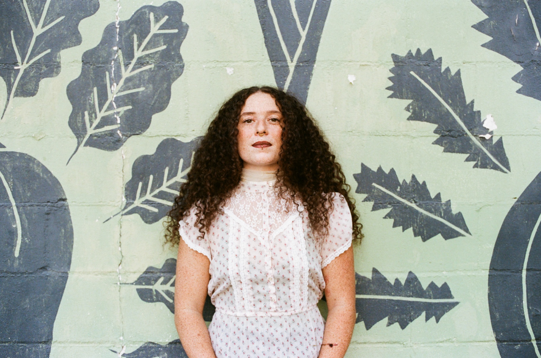 Original 35mm portrait of a woman in a white dress against a green wall painted with leaves
