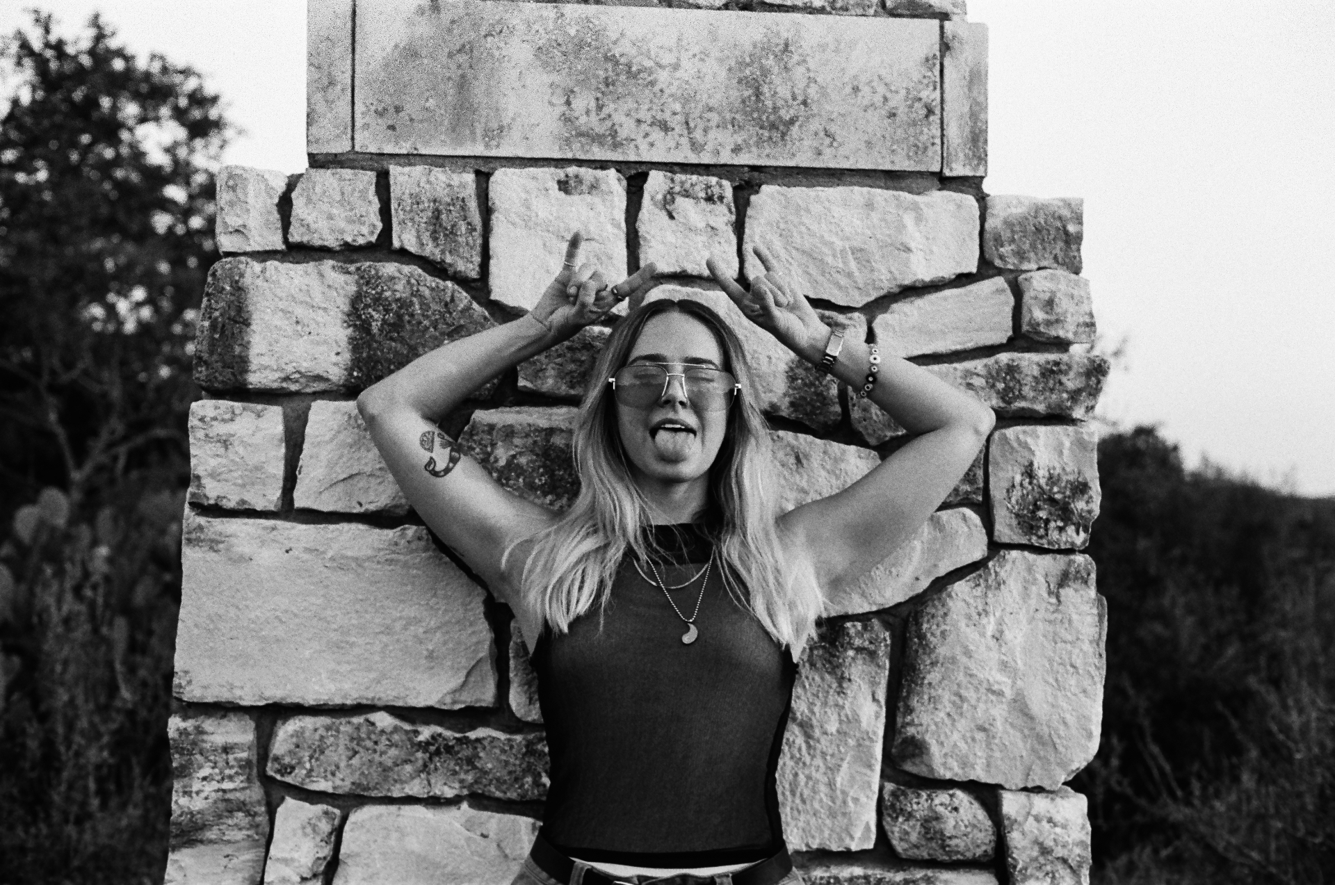 Original black and white 35mm portrait of a woman laughing against a stone wall
